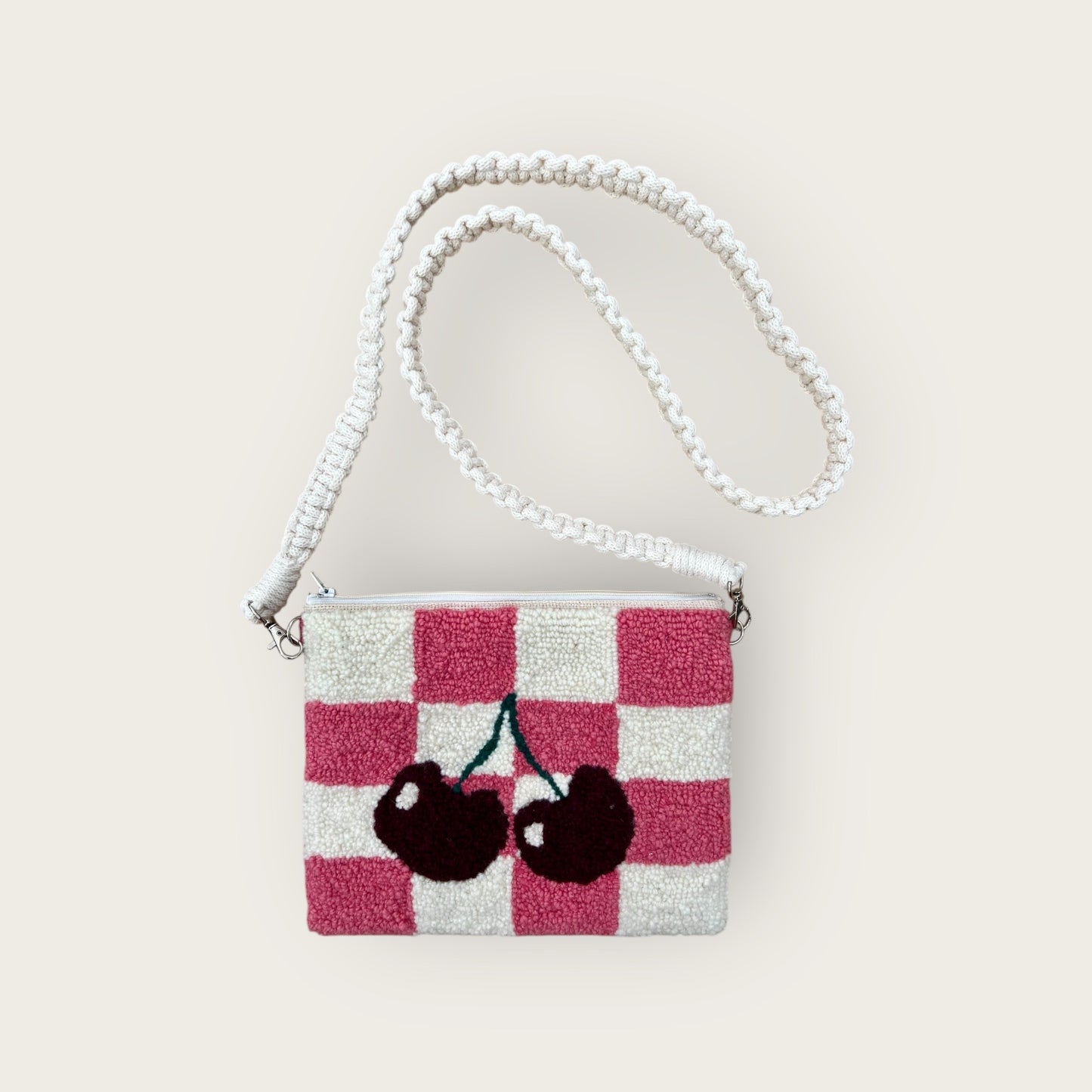 pink and white checkered purse with 2 maroon cherries; zipper on top; white cross body strap