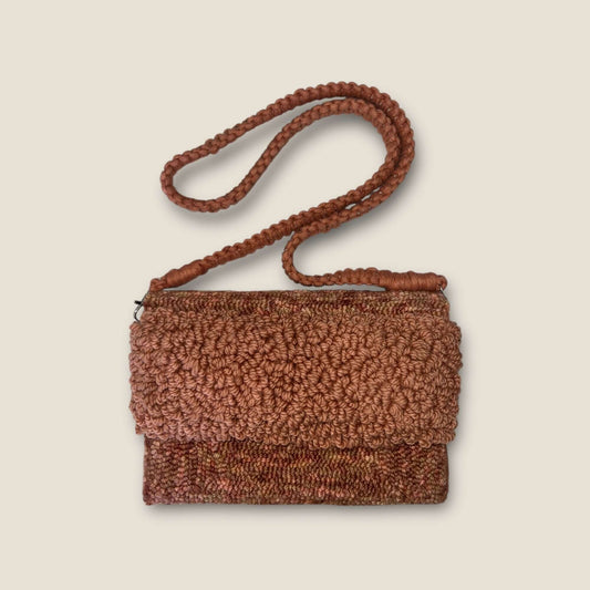 Variagated peach clutch bag with strap, handcrafted with durable fibers for lasting use.